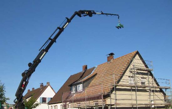 neues Dach im Landkreis Celle - Blick auf einen Kran, der Material auf ein Dach hebt